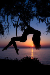 Silhouette woman on beach against sky during sunset