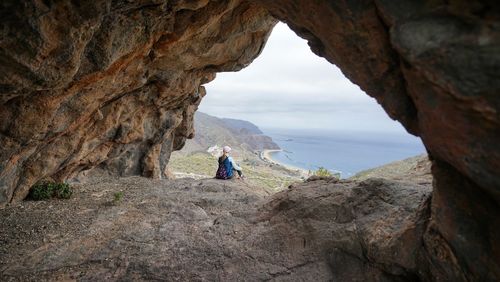 Rear view of man sitting on rock