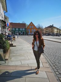 Portrait of young woman standing on footpath