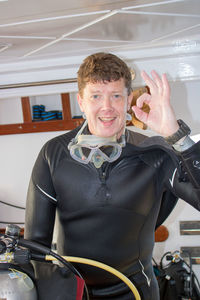 Portrait of smiling scuba diver gesturing ok sign in boat