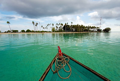 Cropped image of boat on sea against cloudy sky