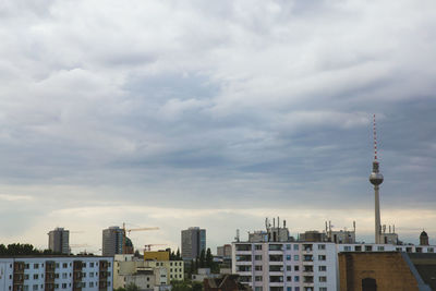 Low angle view of cityscape against cloudy sky