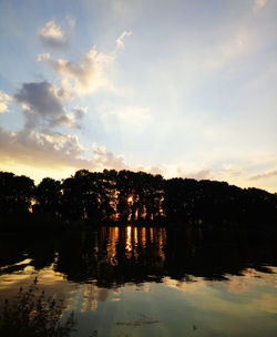 Silhouette trees by lake against sky during sunset