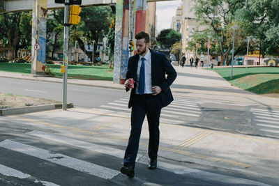 Full length portrait of young man standing on footpath in city