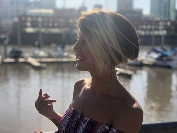 Smiling woman showing obscene gesture while standing in city