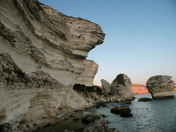 Rock formations in sea against clear sky