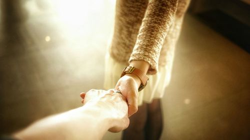 Cropped image of man holding woman hand