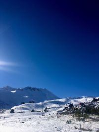Scenic view of snowcapped mountains against clear blue sky