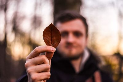 Close-up of man holding autumn leaf