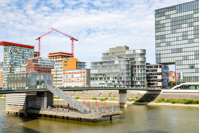 Buildings by river against sky in city