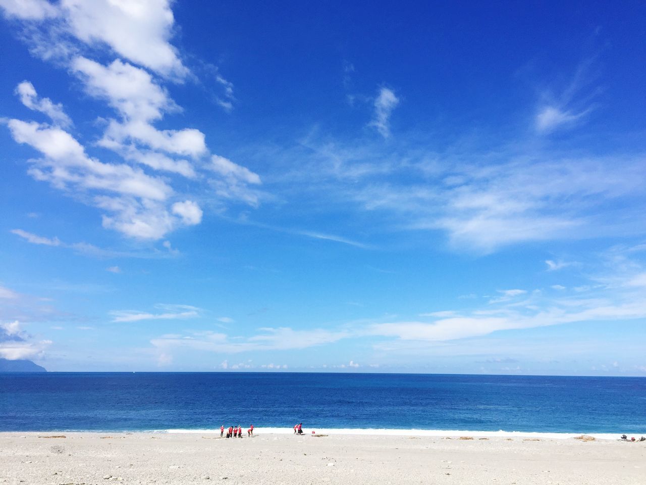 GROUP OF PEOPLE ON BEACH AGAINST BLUE SKY