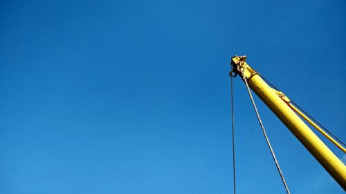 Low angle view of telephone pole against clear blue sky