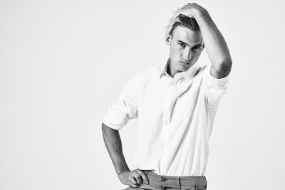 Portrait of young man standing against white background