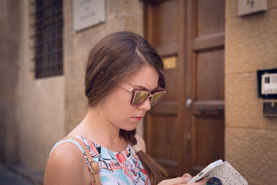 Close-up young woman using smart phone against building