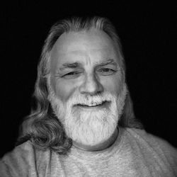 Close-up portrait of smiling man against black background