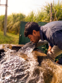 Side view of young man splashing water