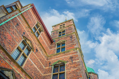 Facade of a brick wall of a building with windows of the royal rosenborg castle against a blue sky