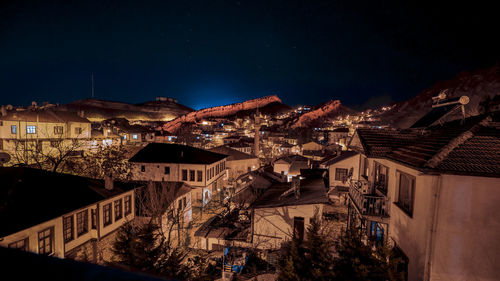 Illuminated buildings in town against sky at night