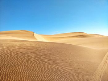 Sand dunes in desert against clear blue sky