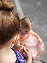 High angle view of siblings holding lollipops on road