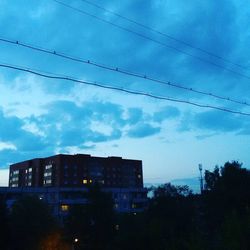 Low angle view of silhouette buildings against blue sky