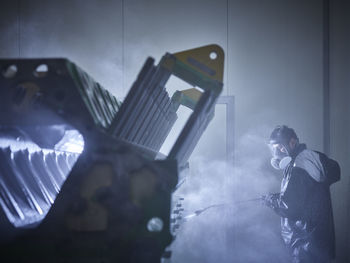 Worker cleaning engine block in washing bay