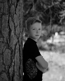 Side view of a boy standing on tree trunk