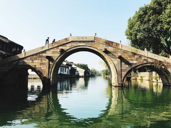 Arch bridge over river against clear sky