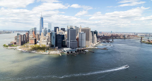 High angle view of east river by modern buildings against cloudy sky