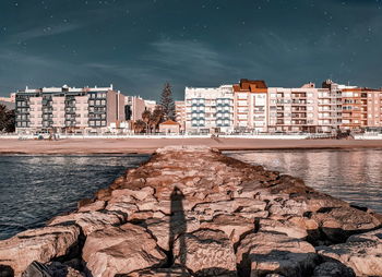 Buildings by sea against sky in city