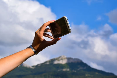 Midsection of man using mobile phone against sky