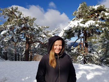 Portrait of smiling young woman standing in snow