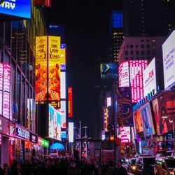 People on illuminated street in city at night