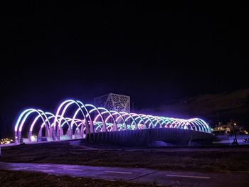 Illuminated bridge against sky at night