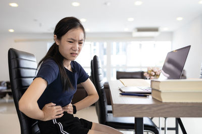 Young woman using mobile phone while sitting on table