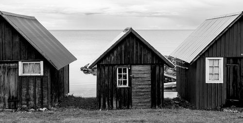 Wooden house on field by buildings against sky