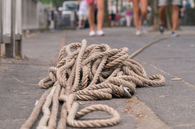 Close-up of rope against people walking on footpath