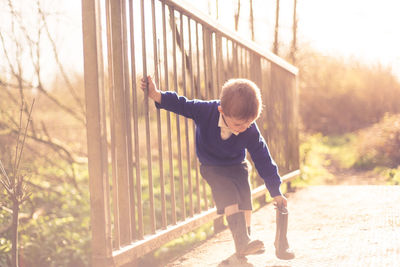 Full length of boy standing by tree