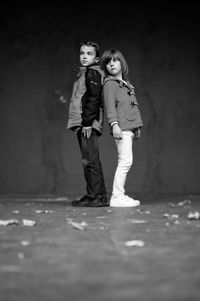 Portrait of boy and girl standing against wall