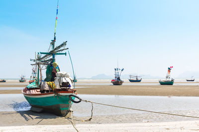Fishing boats moored in sea against clear sky