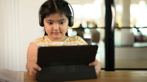 Portrait of girl sitting on table at home