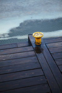 High angle view of yellow cleat on wooden pier over lake