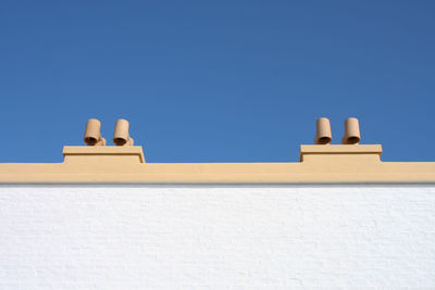 Low angle view of chimney pots against clear blue sky