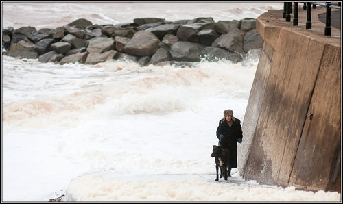 Man standing on rock at sea shore during winter