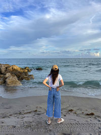 Full length of woman standing at beach against sky