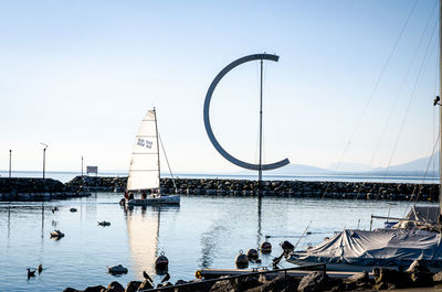 People on sailboat by sea against clear sky