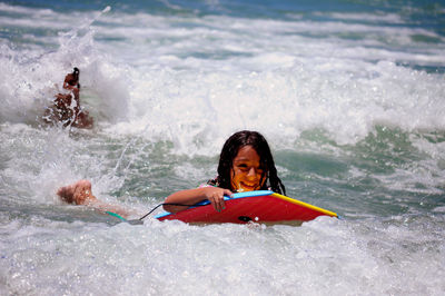 Portrait of girl holding paddleboard in sea