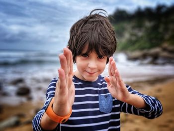 Portrait of boy gesturing while standing on beach