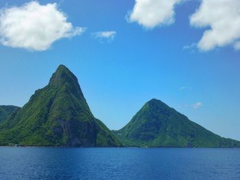 Scenic view of sea and mountains against blue sky