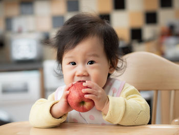 Portrait of cute baby girl eating food at home